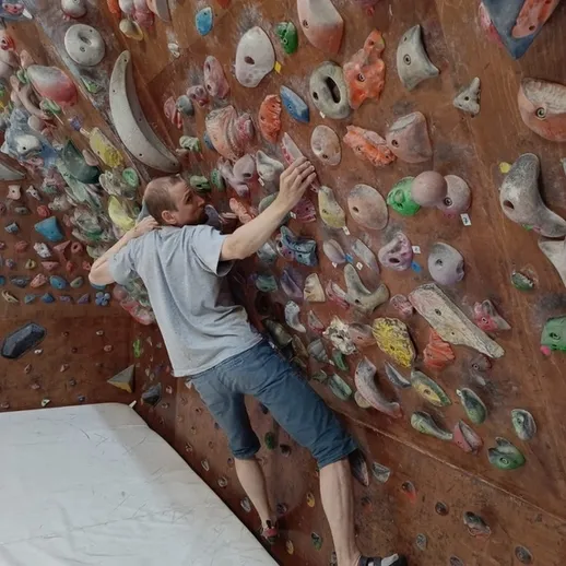 Скальный альпинист занимается боулдерингом в тренировочном зале в Москве в летнее время