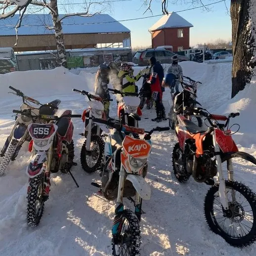 Мотоциклы на парковке в снегу, группа людей готовится к поездке в заснеженной местности