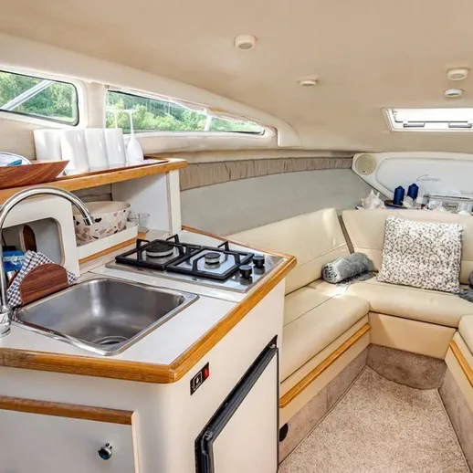 На борту небольшого катера вид на каюту с кухонной зоной и мягкой мебелью