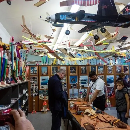 Выставка моделей самолётов в музее авиации, посетители обсуждают экспонаты в апреле