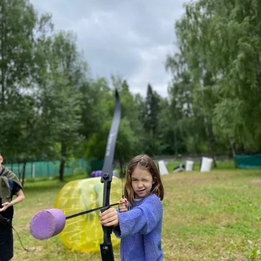Девочка стреляет из лука на спортивной площадке на свежем воздухе