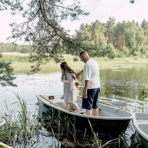 Молодая пара на лодке собирает цветы у берега тихого озера летом