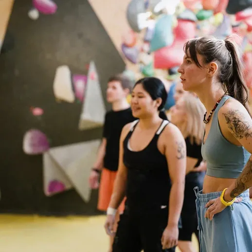 Группа людей занимается скалолазанием в спортзале, тренировка в помещении с блочным стендом