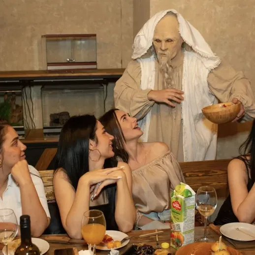 Ужин с загадочным персонажем: группа девушек с удивлением смотрит на необычного гостя в непринужденной обстановке