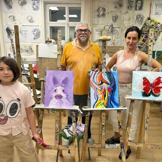 Детский художественный класс в студии, участники работают над картинами в теплой атмосфере творческого вечера