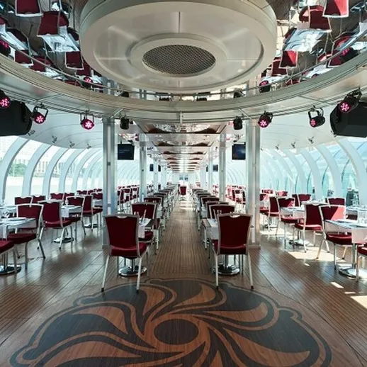 Элегантный интерьер современного ресторана на теплоходе с красными стульями и панорамными окнами вдоль реки