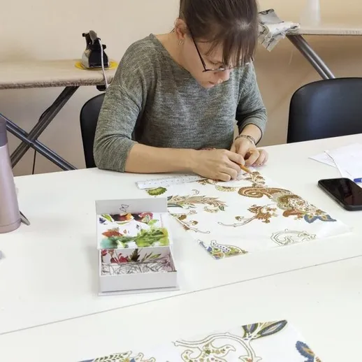 Женщина шьет декоративную ткань в мастерской во время занятия рукоделием