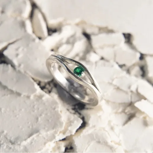 Круглая серебряная кольца с черным камнем на треснувшей белой поверхности