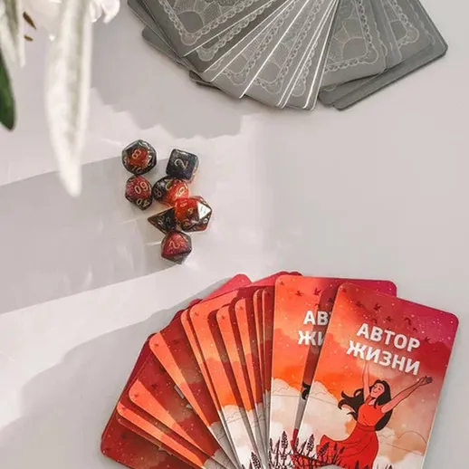 Карты для настольной игры и игральные кости на белом столе с искусственными цветами