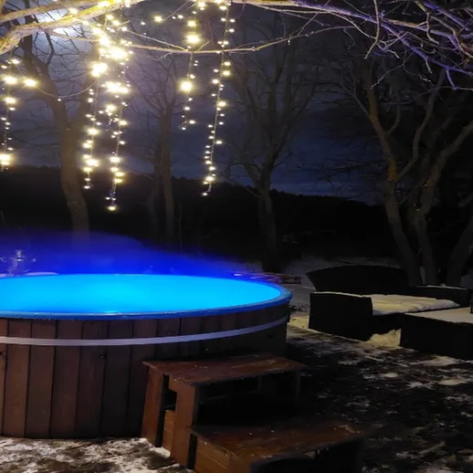 Уютный вечер у горячей купели с подводной подсветкой в снежном лесу