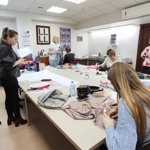 Ученики занимаются шитьем в классе модного дизайна во время практических занятий
