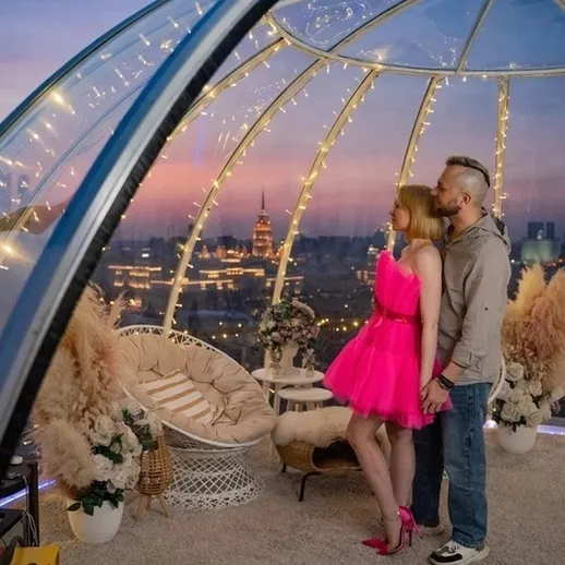 Романтический вечер в стеклянном павильоне с видом на город в сумерках