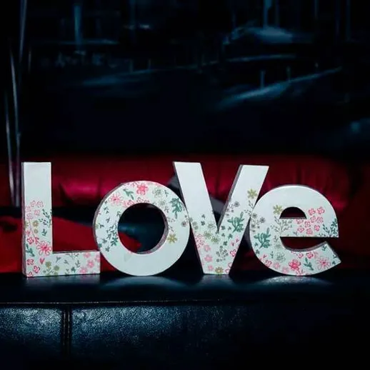 Красивые буквы LOVE на черном фоне в уютной обстановке с красной декоративной подушкой