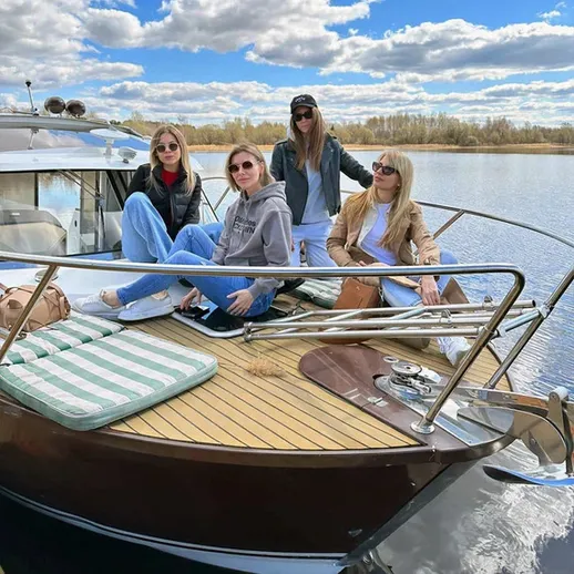 Четыре девушки отдыхают на яхте на фоне спокойного водоема в ясный осенний день