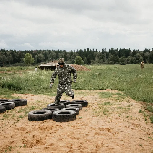 Военный практикует навыки передвижения на полосе препятствий с покрышками на тренировочном полигоне в лесу летом