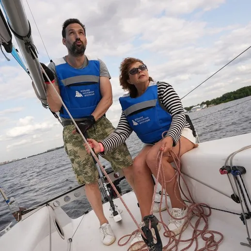 Два человека на парусной лодке учатся управлять судном на воде в ясный день
