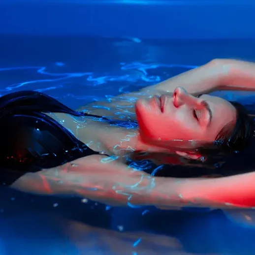Женщина расслабляется в воде с ярким освещением в вечернее время