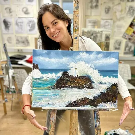Женщина у мольберта с картиной морского пейзажа и маяка в художественной студии