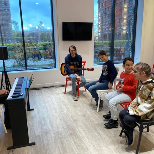 Музыкальный урок в уютном центре с детьми, играющими на гитаре и фортепиано