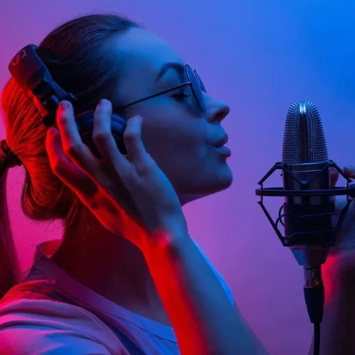 Молодая женщина поет в студии звукозаписи с микрофоном под ярким освещением в вечернее время