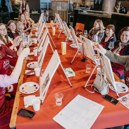 Группа людей отмечает завершение мастер-класса по живописи в ресторане