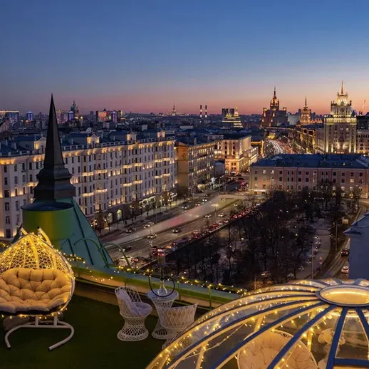 Ночной вид на Москву с крыши здания, освещенный город и уютные кресла на террасе