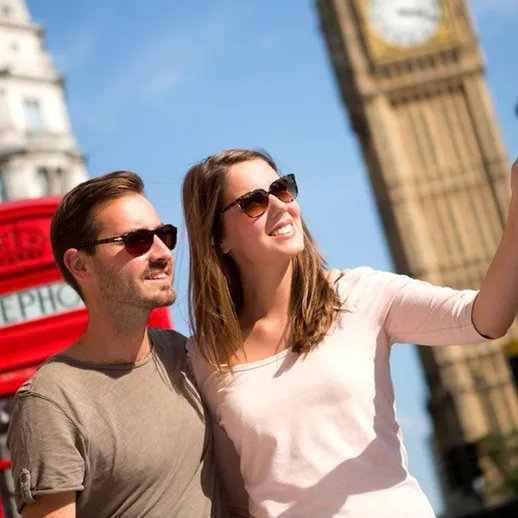 Молодая пара наслаждается солнечным днем у Биг-Бена и красной телефонной будки в Лондоне