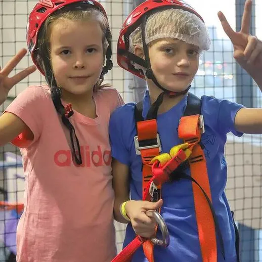 Дети с касками и страховочными жилетами на занятиях по скалолазанию в спортивном центре