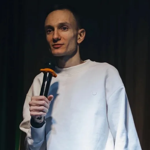 Молодой человек выступает на сцене с микрофоном в уютном клубе