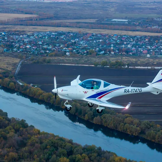 Летящий над рекой легкий самолет с красивым пейзажем на фоне, осень, Россия