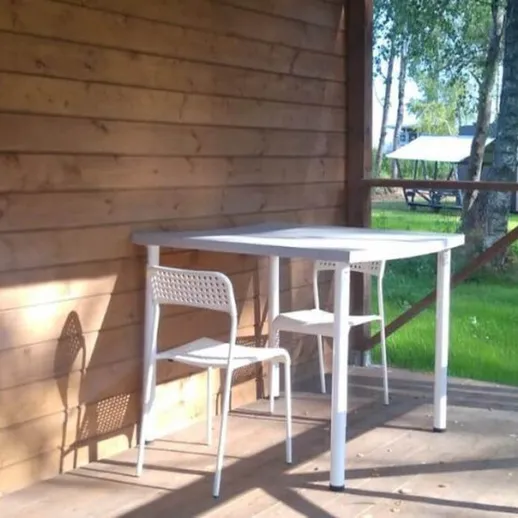 Уютная веранда с белым столом и стульями в зеленом саду