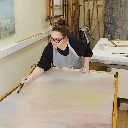 Художник создает абстрактную картину в мастерской с натуральным освещением и холстом