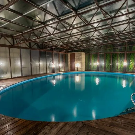Закрытый бассейн с чистой водой и уютной атмосферой, освещенный мягким светом в вечернее время