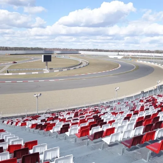 Трасса для гонок с трибунами и зелеными просторами, расположенная на фоне облачного неба