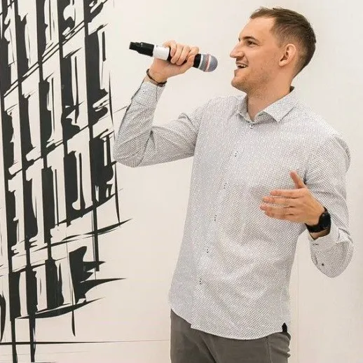 Молодой человек говорит на микрофон в современном здании