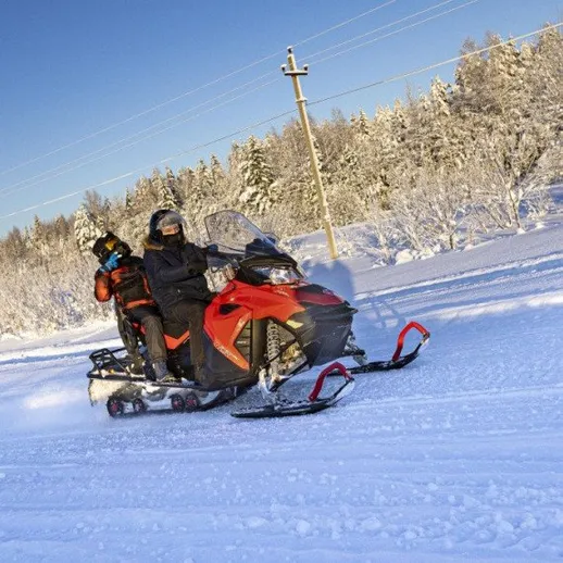 Катание на снегоходах по снежному деревенскому пейзажу в ясный зимний день