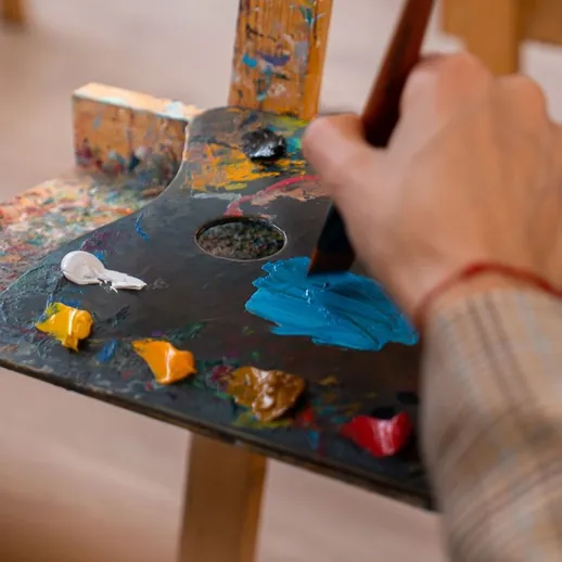 Художник смешивает краски на палитре в мастерской во время творческого занятия