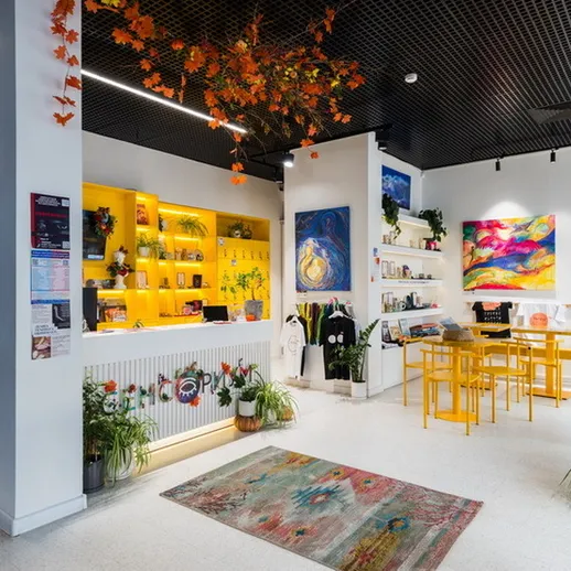 Яркое кафе с цветами и картинами, уютной атмосферой и желтыми стульями в современном интерьере