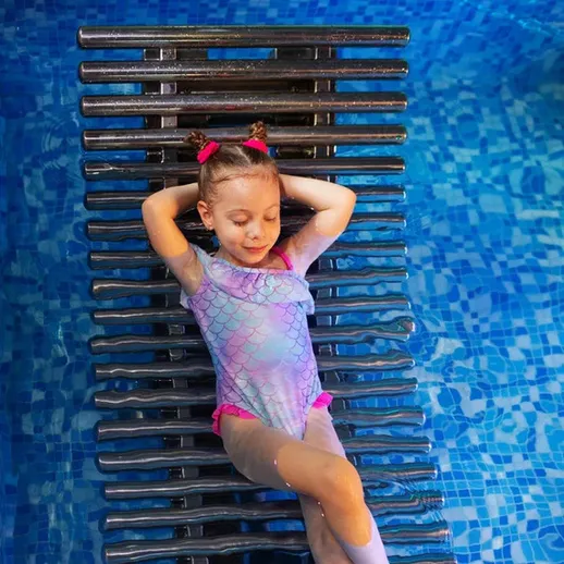 Девочка отдыхает на шезлонге у бассейна в солнечный день