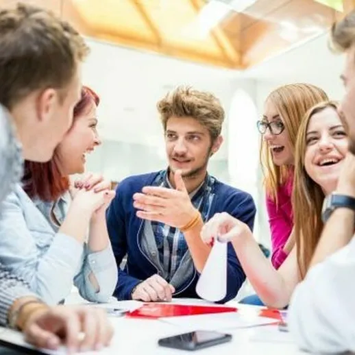 Группа молодых людей обсуждает идеи в кафе, наслаждаясь общением и дружеской атмосферой в светлом помещении