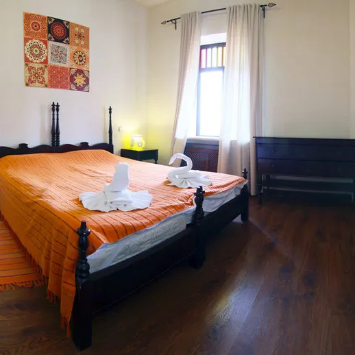 Уютная спальня с оранжевым покрывалом и декоративными элементами в солнечном помещении