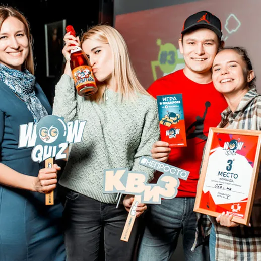 Команда веселых участников квиза на мероприятии в клубе, где они празднуют победу и демонстрируют призы в феврале