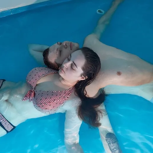 Парочка расслабляется в бассейне, наслаждаясь моментом в солнечный день