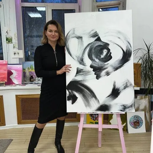 Женщина представляет абстрактную картину в художественной студии во время вечернего мастер-класса