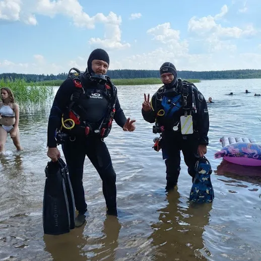 Два дайвера на мелководье озера в ясный солнечный день, готовящиеся к погружению в водоем
