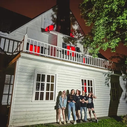 Группа друзей на фоне старого дома в темноте с яркими окнами