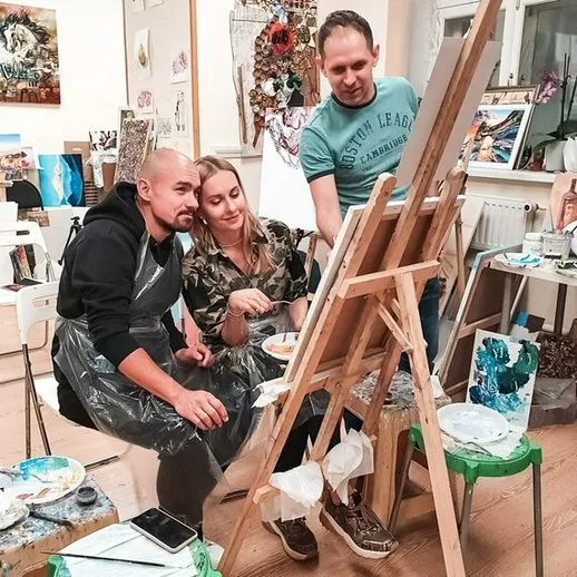 Урок живописи в арт-студии с участниками, работающими над своими картинами в уютной атмосфере вечером