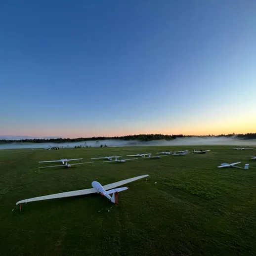 Силуэты планеров на травяном поле в спокойное утро перед восходом солнца