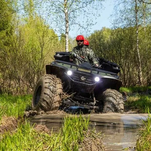 Два человека на квадроцикле в лесу во время весенней прогулки по грязным дорожкам