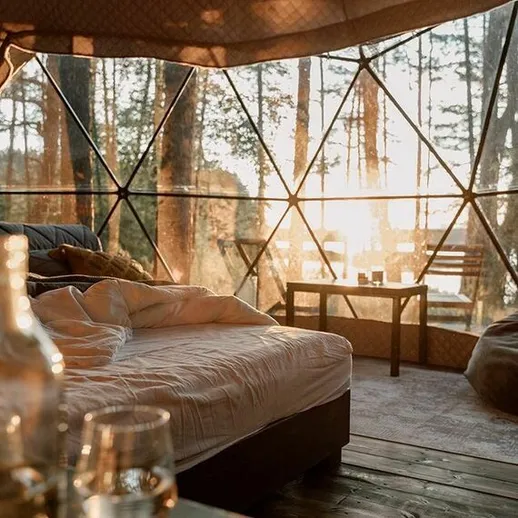 Уютное глэмпинг-проживание в геодезическом куполе на фоне заката в лесу